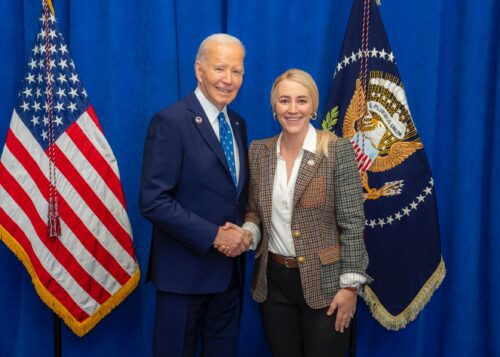 President Joe Biden and Anna Laymon shaking hands in front of the American flag.